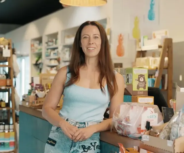 Coco, owner of Coco's Wealth of Health, standing at the counter of her health food shop