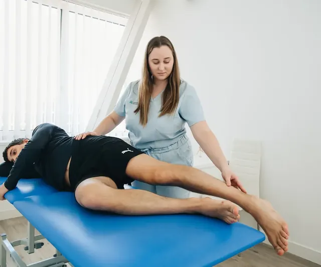 A physiotherapist treating a patient on a treatment table in a bright clinic room